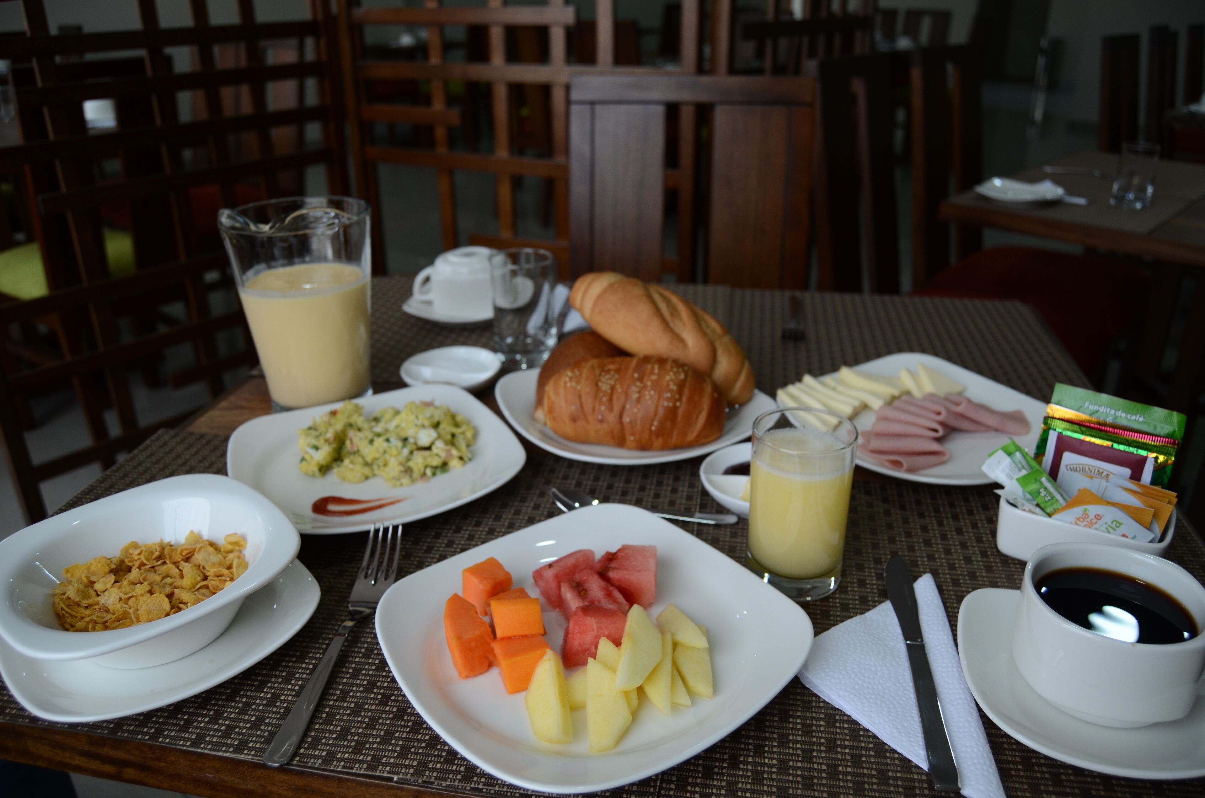 A breakfast table with plates of food, a glass of juice, and a cup of coffee.