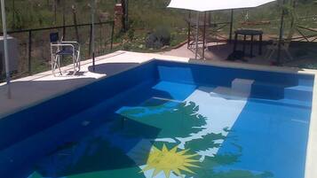 Una piscina al aire libre, sombrillas, sillones reclinables de piscina