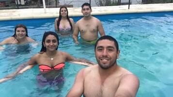 Una piscina al aire libre, sombrillas, sillones reclinables de piscina