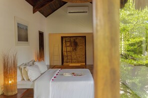 Quarto com cama, quadro, escada e parede de pedra.