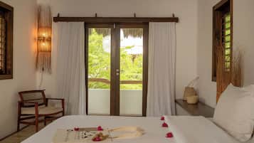 Habitación de hotel con cama, una silla, una mesita y vista a zonas verdes.