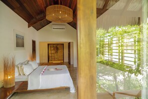 A bedroom with a bed, a wooden ceiling, a hanging light fixture, and a view of greenery outside. - Villa Alegria - La Villa Group (Jijoca de Jericoacoara)