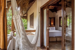 Una habitación con cama, una hamaca y vista a zonas verdes.