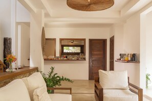 A modern living room with a sofa, a coffee table, and a dining area with a counter and chairs. - Villa Alegria - La Villa Group (Jijoca de Jericoacoara)