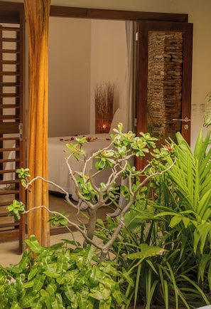Una habitación con cama, puerta de madera y pared de piedra.