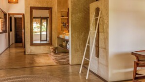 A spacious hallway with a wooden floor, a ladder leaning against a wall, and a door leading to a room with a view of greenery. - Villa Alegria - La Villa Group (Jijoca de Jericoacoara)