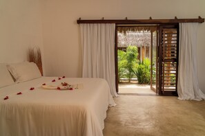 Un dormitorio con cama, una puerta de madera que da a un balcón y vistas de vegetación.
