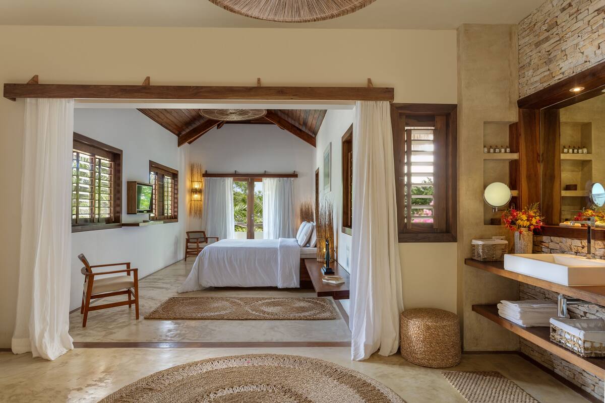 A spacious bedroom with a large bed, a wooden chair, and a vanity with a mirror.