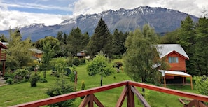 Un chalet de montagne doté d’une terrasse en bois et offrant une vue sur des montagnes enneigées.