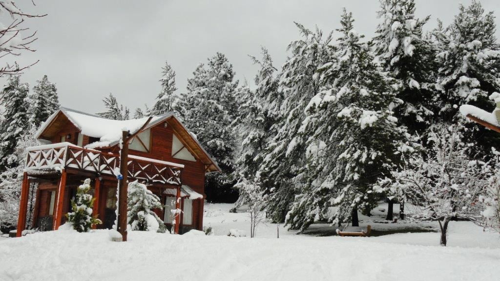 A wooden cabin with a balcony, surrounded by snow-covered trees.