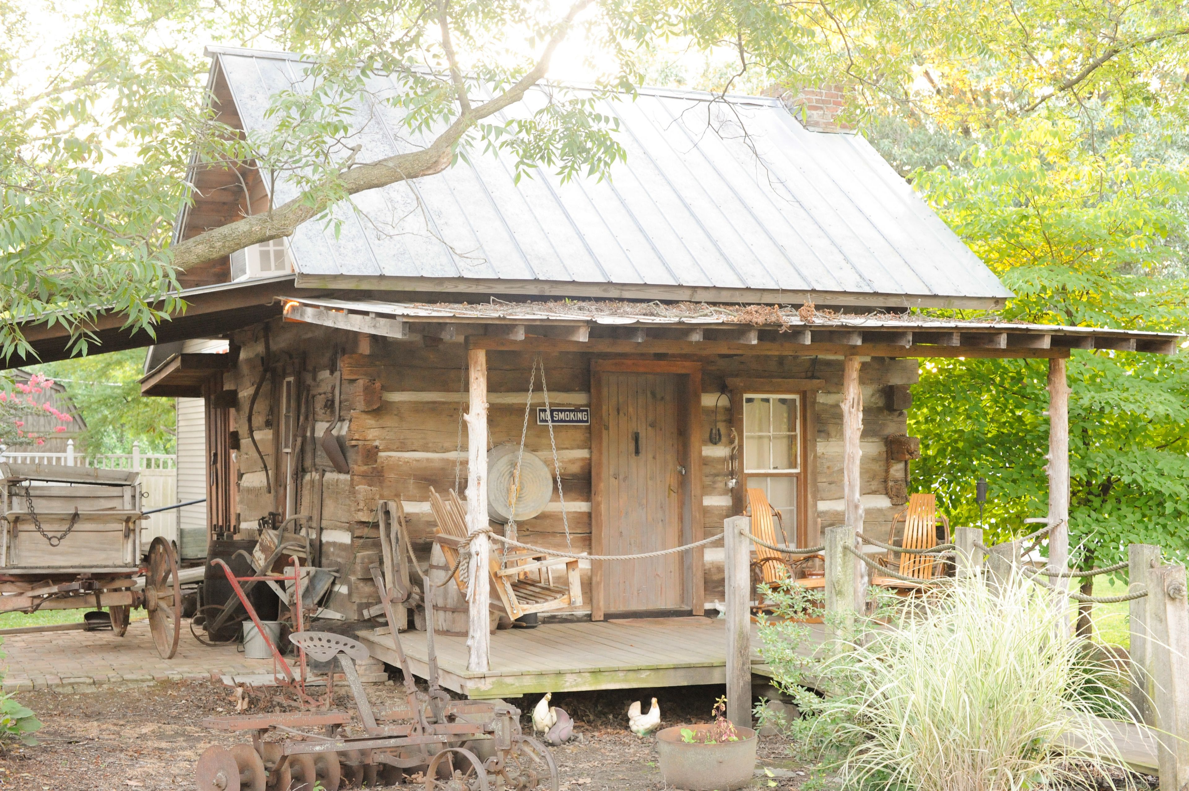 A rustic log cabin with a porch, a swing, and a 'No Smoking' sign.