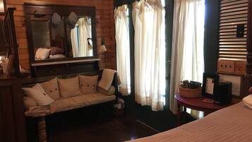 Una habitación acogedora con pared de madera, un sofá con cojines, un espejo y cortinas.