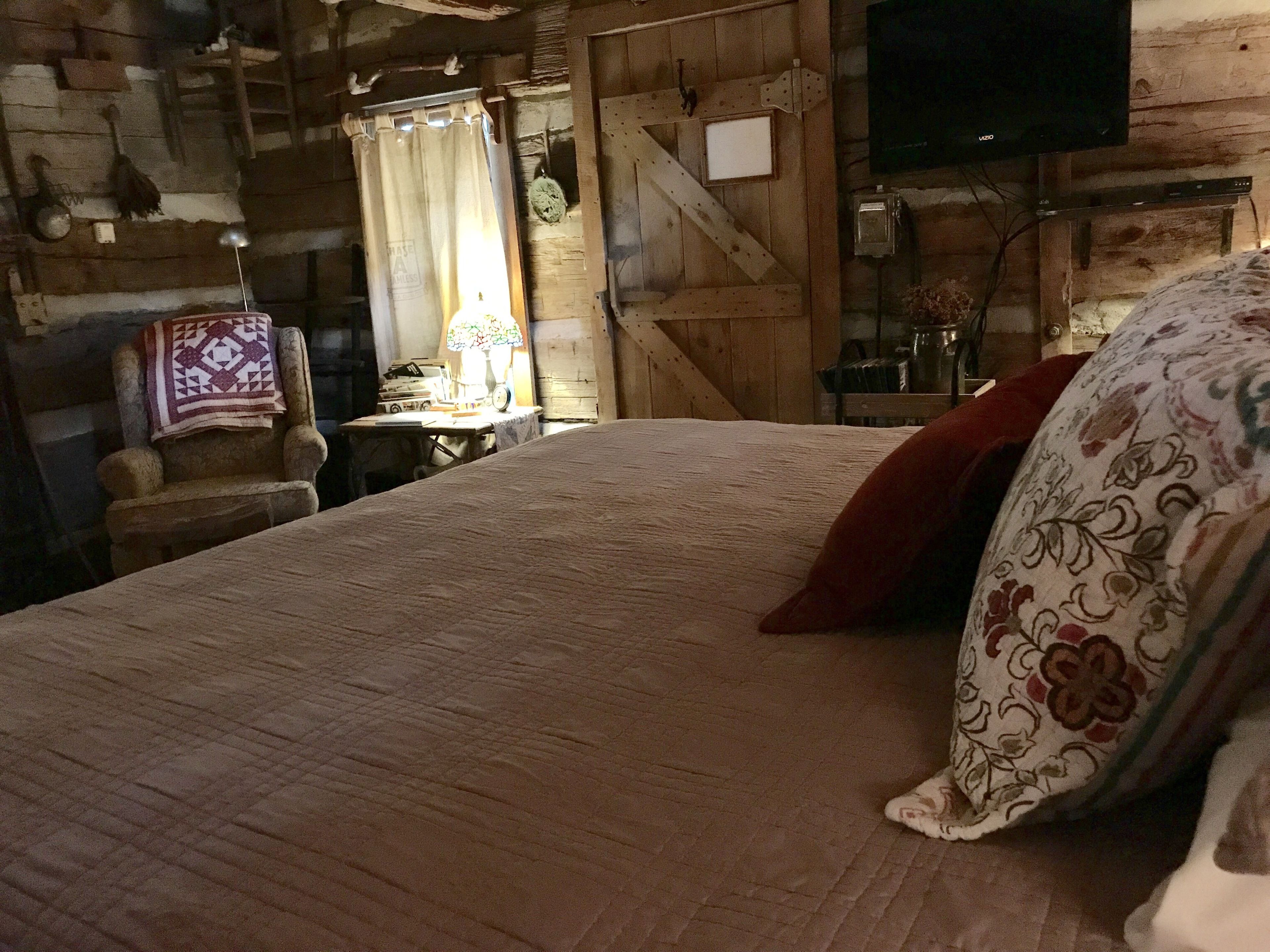 A rustic room with a wooden bed, a television, and a lamp.