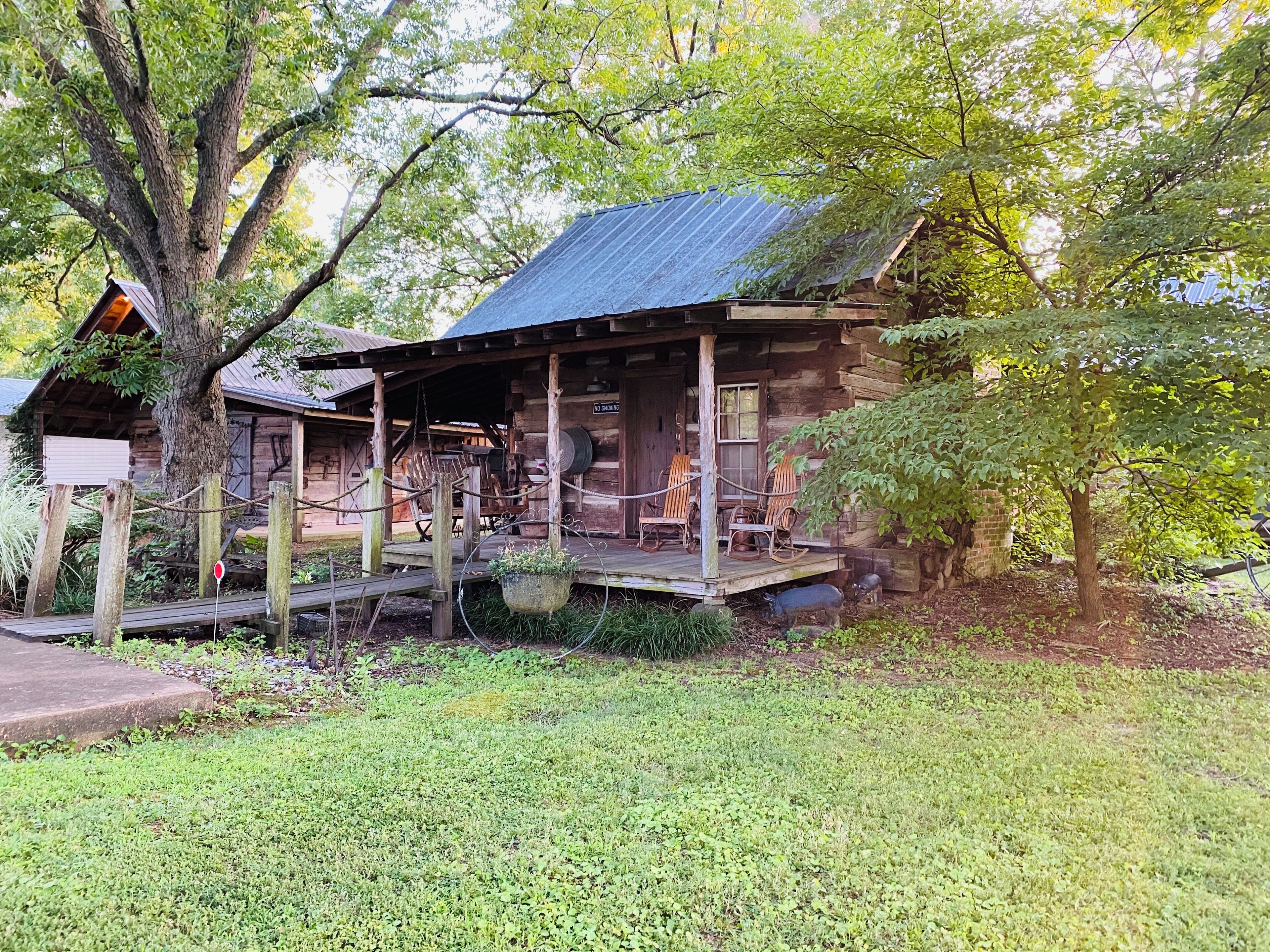 A rustic log cabin with a porch, rocking chairs, and a sign indicating 'No Smoking'.