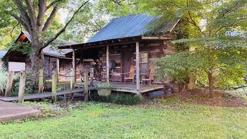 A rustic log cabin with a porch, rocking chairs, and a sign indicating 'No Smoking'.