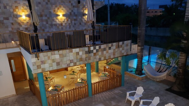 A two-story building with a pool area, outdoor seating, and a hammock.