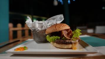 Una comida con una hamburguesa, lechuga, salsa, un pequeño acompañamiento y un cesto de tostadas.
