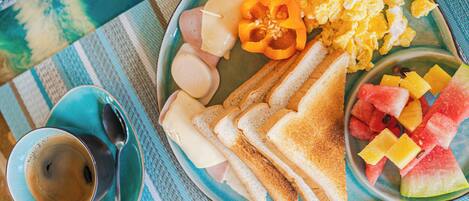 A plate with scrambled eggs, ham, cheese, toast, and fruit on a table with a blue and white striped placemat.