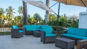 A patio area with outdoor furniture, including sofas and chairs, and a large umbrella providing shade.