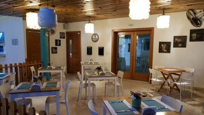A dining area with wooden tables and chairs, a wooden ceiling, and various wall decorations.