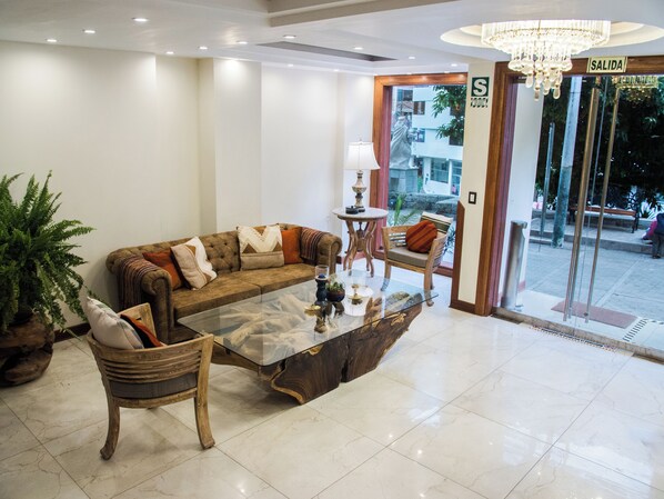 En lobby med sofa, stole, sofabord, lampe og et skilt med teksten "SALIDA".