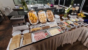Un bufé con diversos alimentos, como pan, pasteles y carnes.