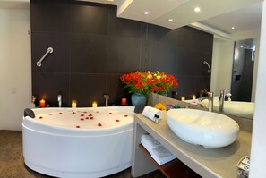 A modern bathroom with a large bathtub, a vanity with a sink, and a mirror. - Jaya Hotel Machu Picchu (Ancón)