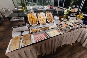 Un bufé con diversos alimentos, como pan, pasteles y carnes.