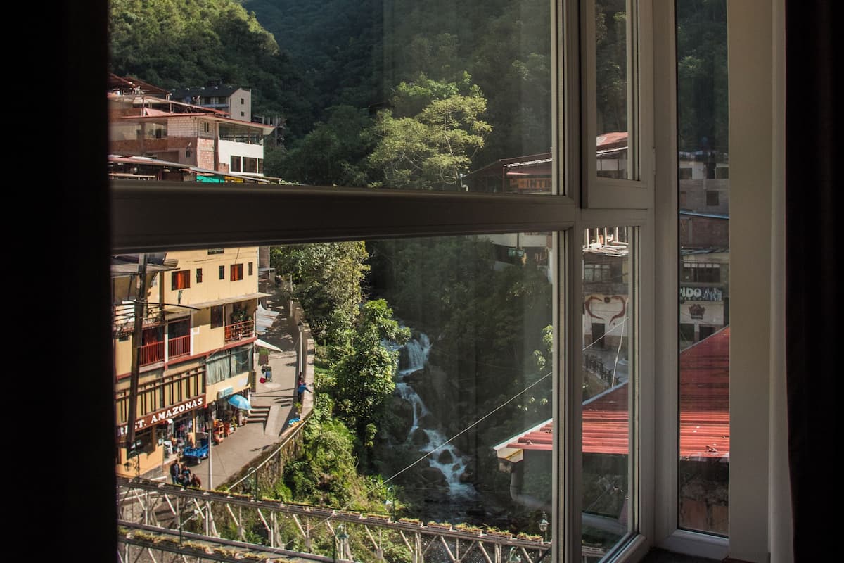 Une pièce dotée d’une grande fenêtre donnant sur un paysage montagneux, d’un escalier et offrant une vue sur une rivière.