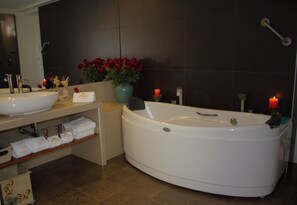 Un baño moderno con una bañera grande, un lavabo doble y un mueble de tocador con toallas.