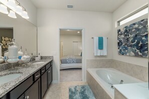 A modern bathroom with a large sink, a bathtub, and a shower. There is a doorway leading to a bedroom. - Windsor at Westside Resort Homes (Kissimmee)