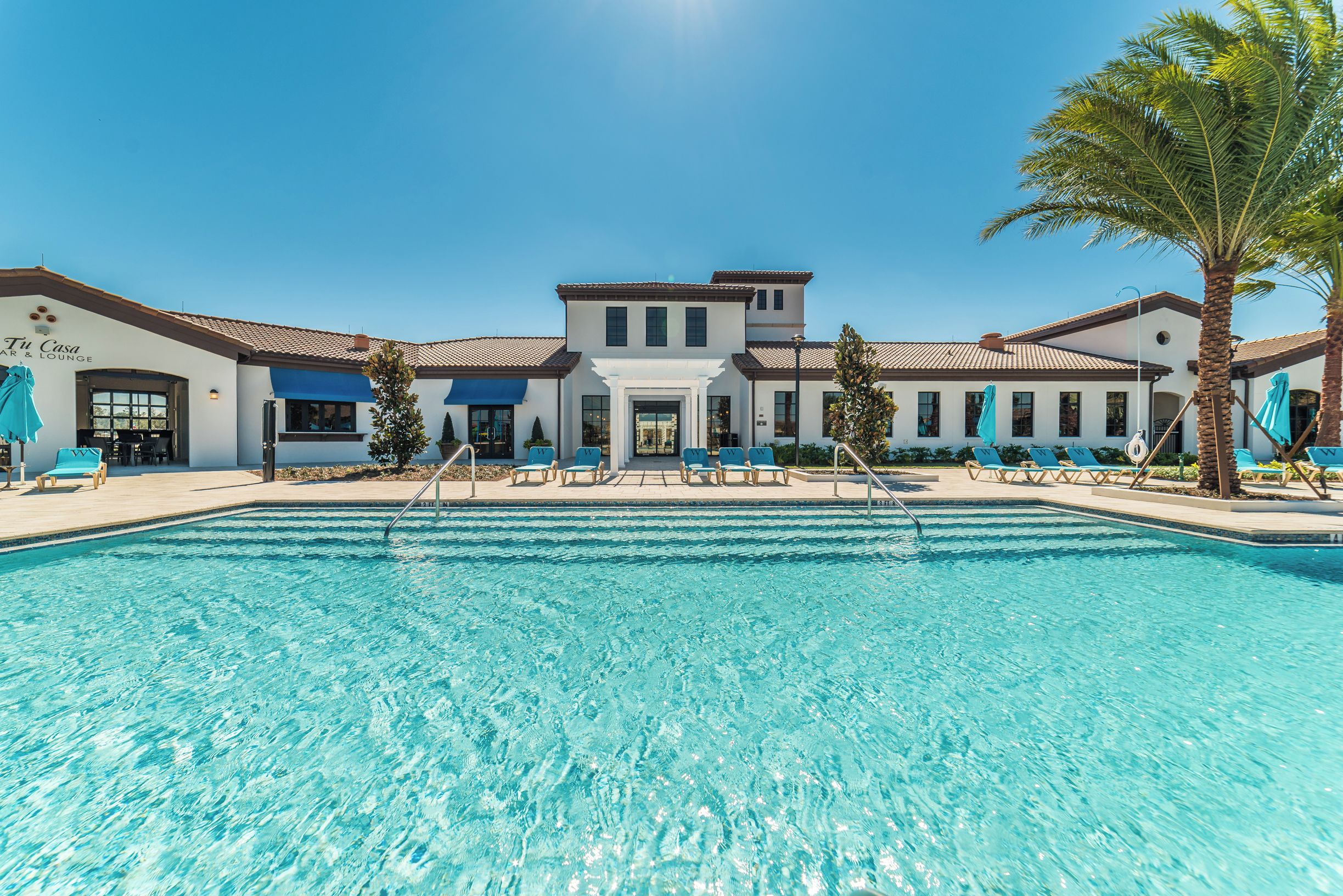Ein Hotel mit Swimmingpool, einer Lounge und Palmen.