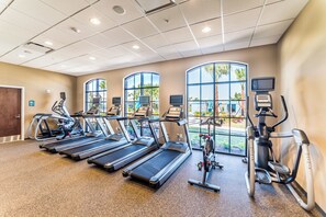 A gym with treadmills, elliptical machines, and exercise bikes. - Windsor at Westside Resort Homes (Kissimmee)