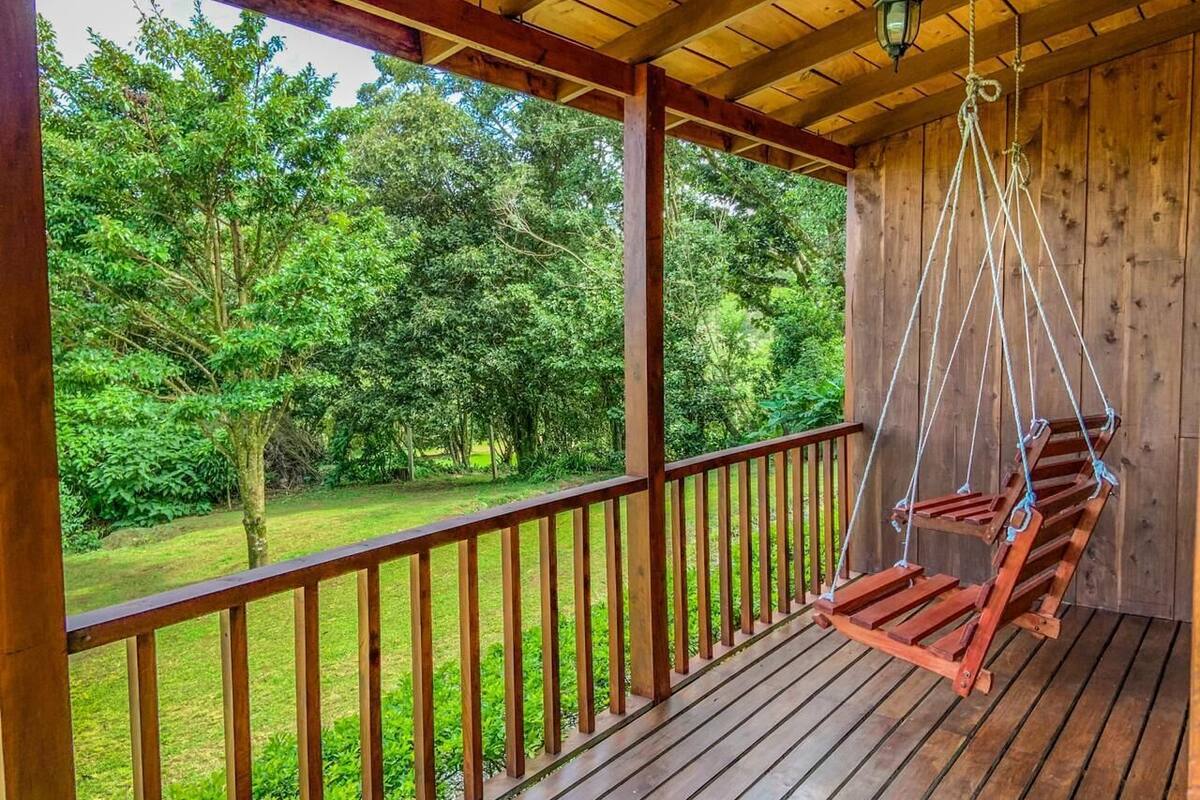 A wooden deck with a swing chair overlooking a lush green landscape.