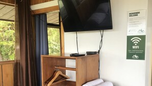A wooden bunk bed with a TV mounted above it, a towel rack, and a small shelf with towels. - Casa Campo Verde (Monteverde)