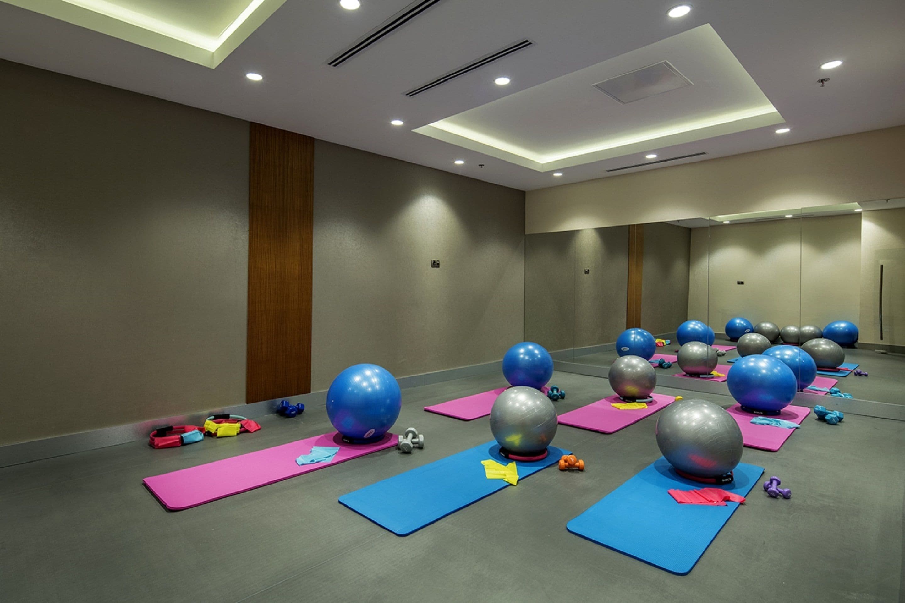 A spacious room with exercise equipment, including large exercise balls and yoga mats, arranged on the floor.