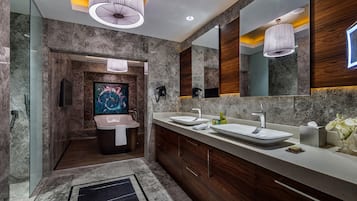 A modern bathroom with a large mirror, two sinks, a bathtub, and a shower area.