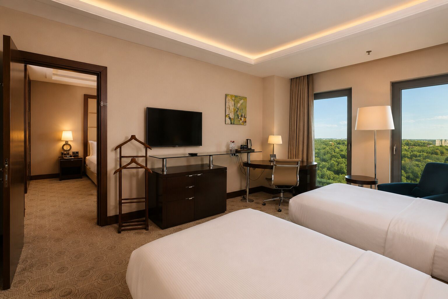 A hotel room with two beds, a desk, a TV, a chair, and a view of the city.
