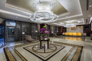 A hotel lobby with a large chandelier, a reception desk, and a seating area with a patterned floor. - DoubleTree by Hilton Istanbul Topkapi (Istanbul)