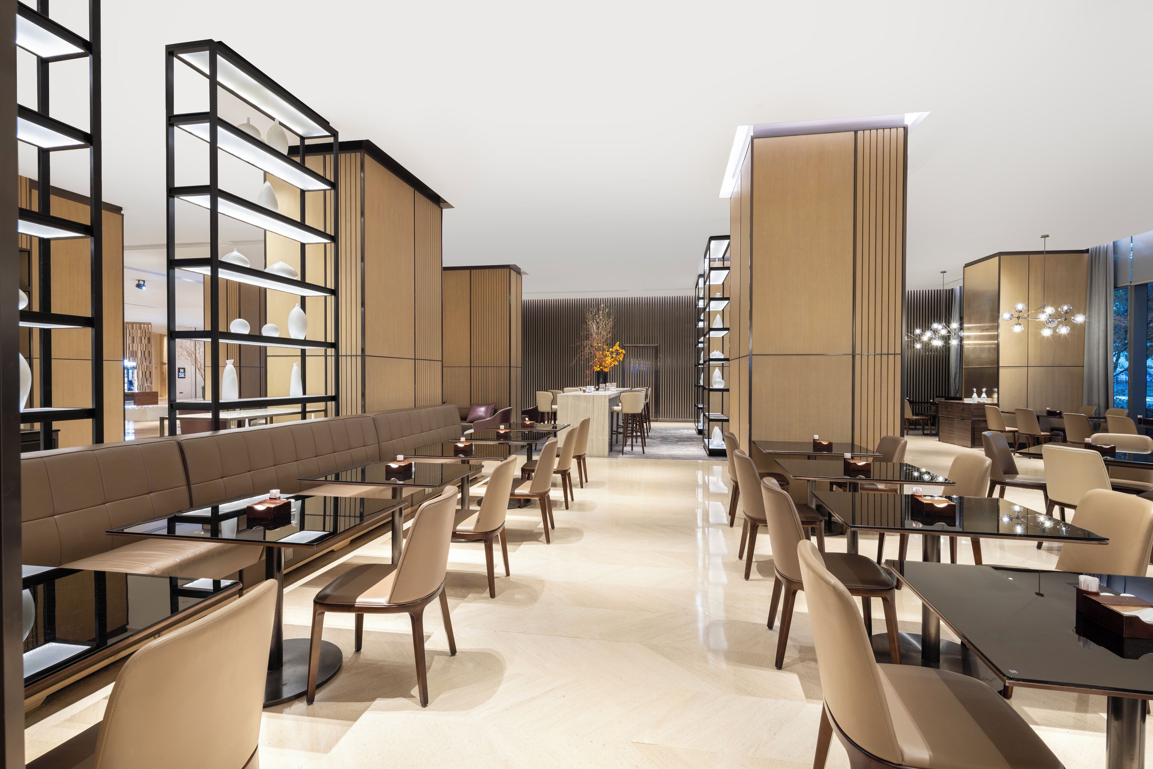 A modern hotel lobby with a long reception desk, seating area, and a decorative vase in the center.