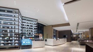 A modern hotel lobby with a reception desk, a seating area, and a display of decorative items. - Hyatt House Shanghai Hongqiao CBD (Shanghai)