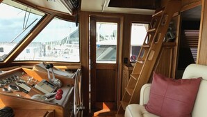 A cozy interior with a wooden console, a cushioned seat, and a view through a door. - Southern Comfort Yacht (Charleston)