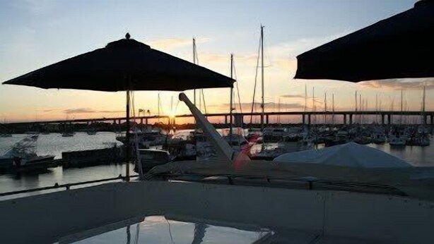 A marina with boats docked, a pier in the background, and umbrellas providing shade. - Southern Comfort Yacht (Charleston)