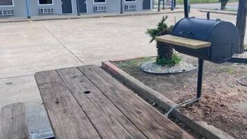A picnic table with a grill in a courtyard.