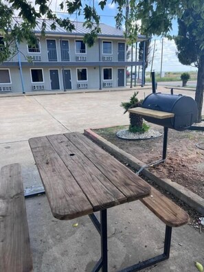 A picnic table with a grill in a courtyard.