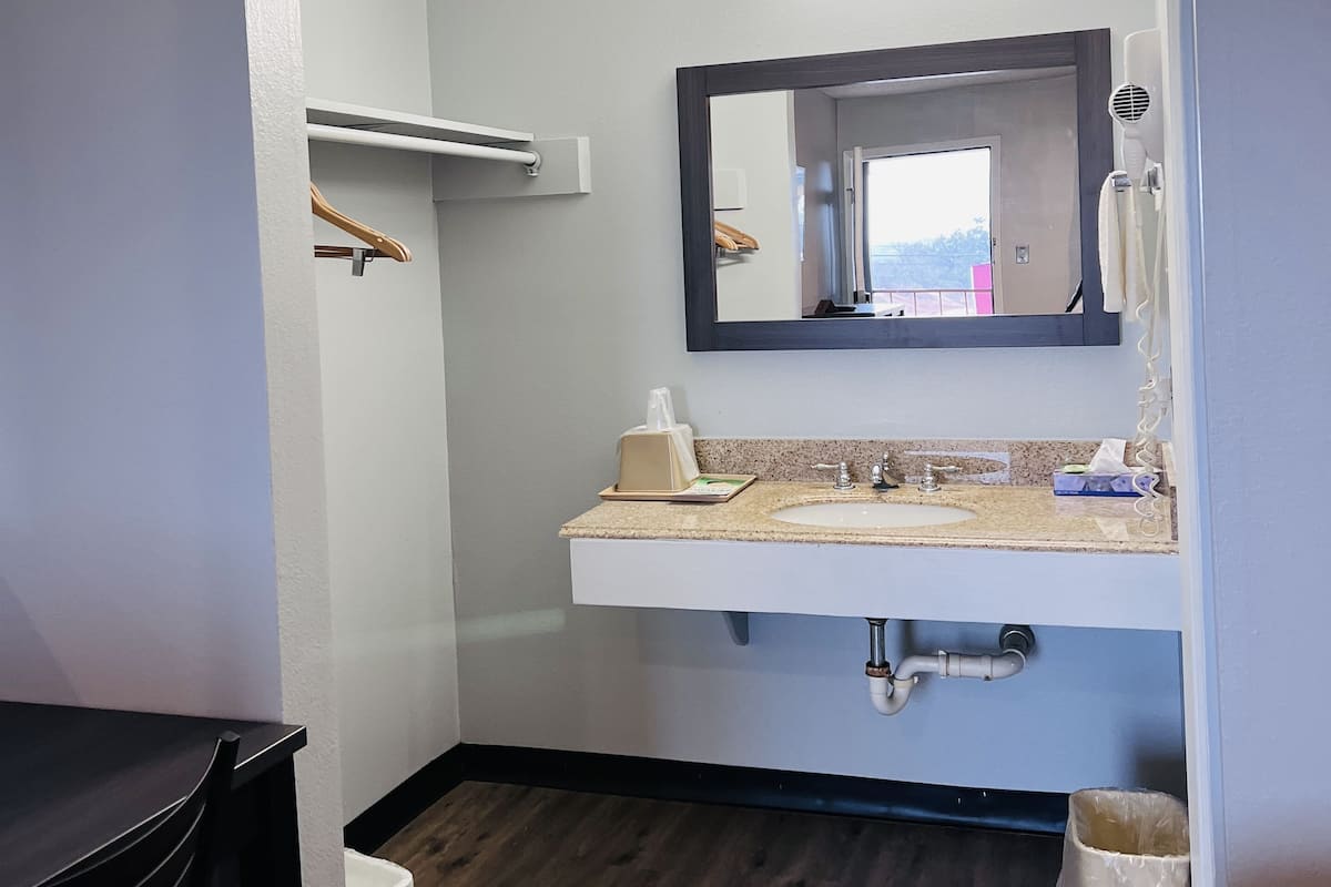 Un baño de hotel con lavamanos, espejo, toallero y suelo de madera.