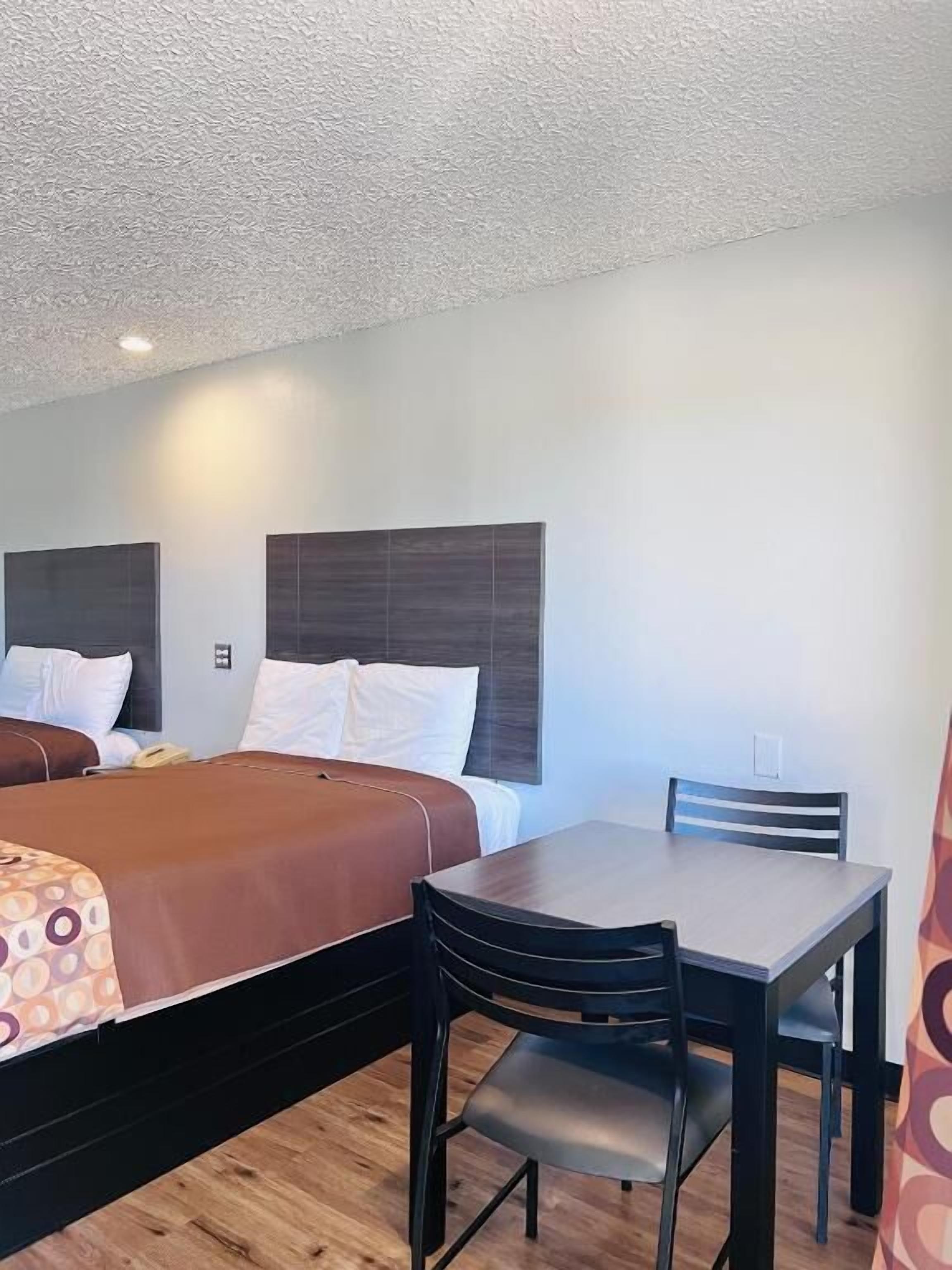 Una habitación de hotel con dos camas, una mesita y una silla.