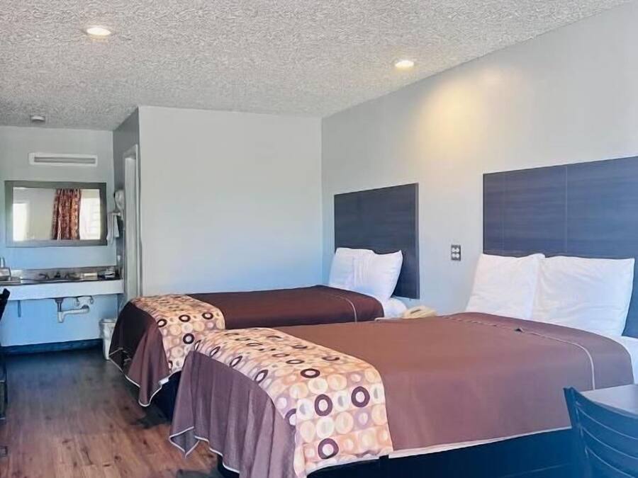 A hotel room with two beds, a wooden floor, and a small table.