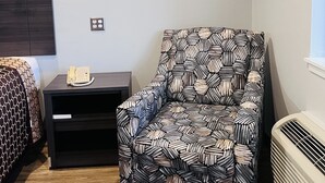 A modern room with a patterned armchair, a small table with a telephone, and a heater.