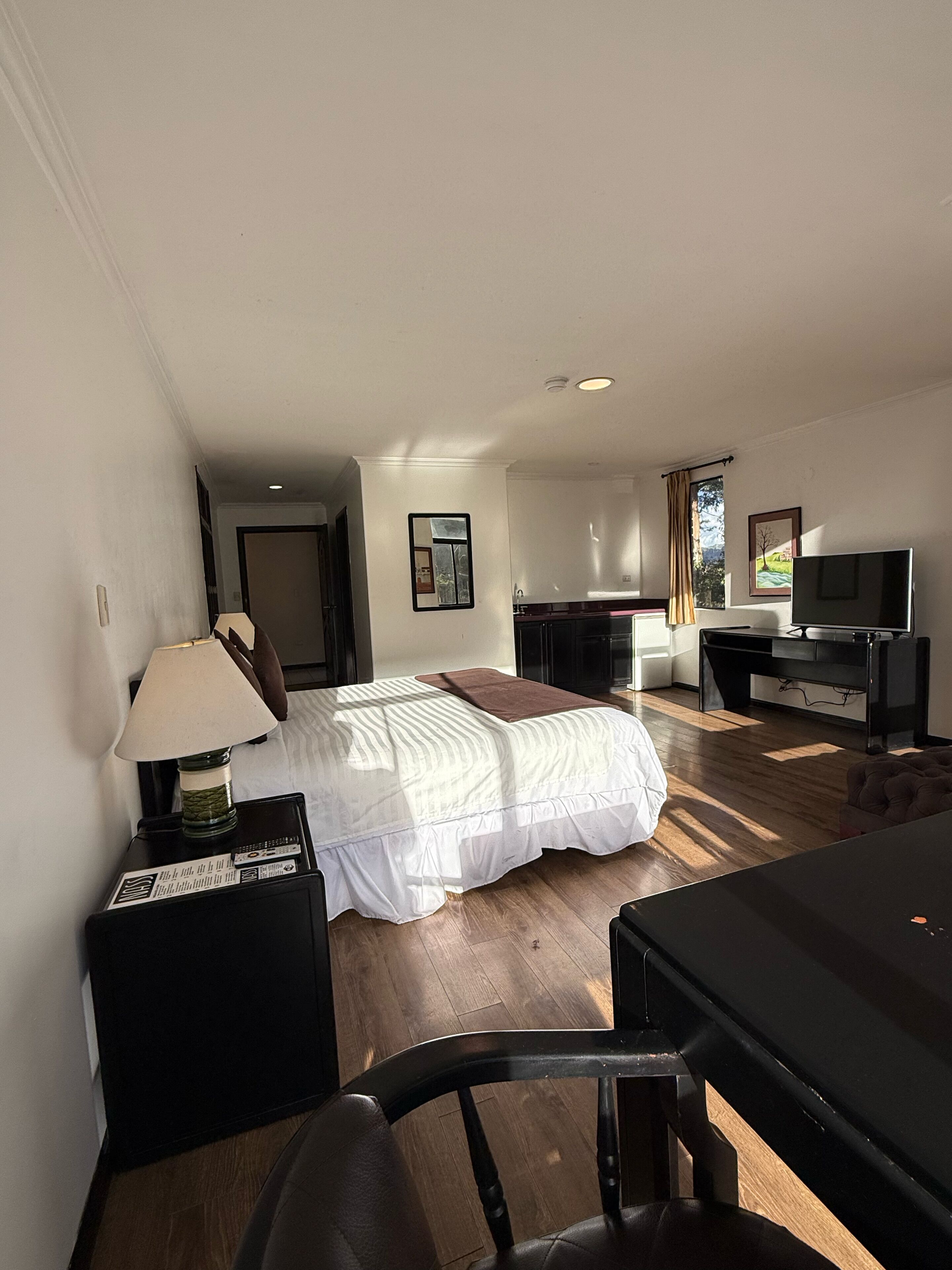 Een hotelkamer met een bed, een bureau, een stoel, een televisie en een lamp.